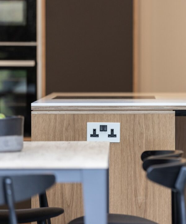 white and black double socket insatlled on the end of a wooden and white kitchen island