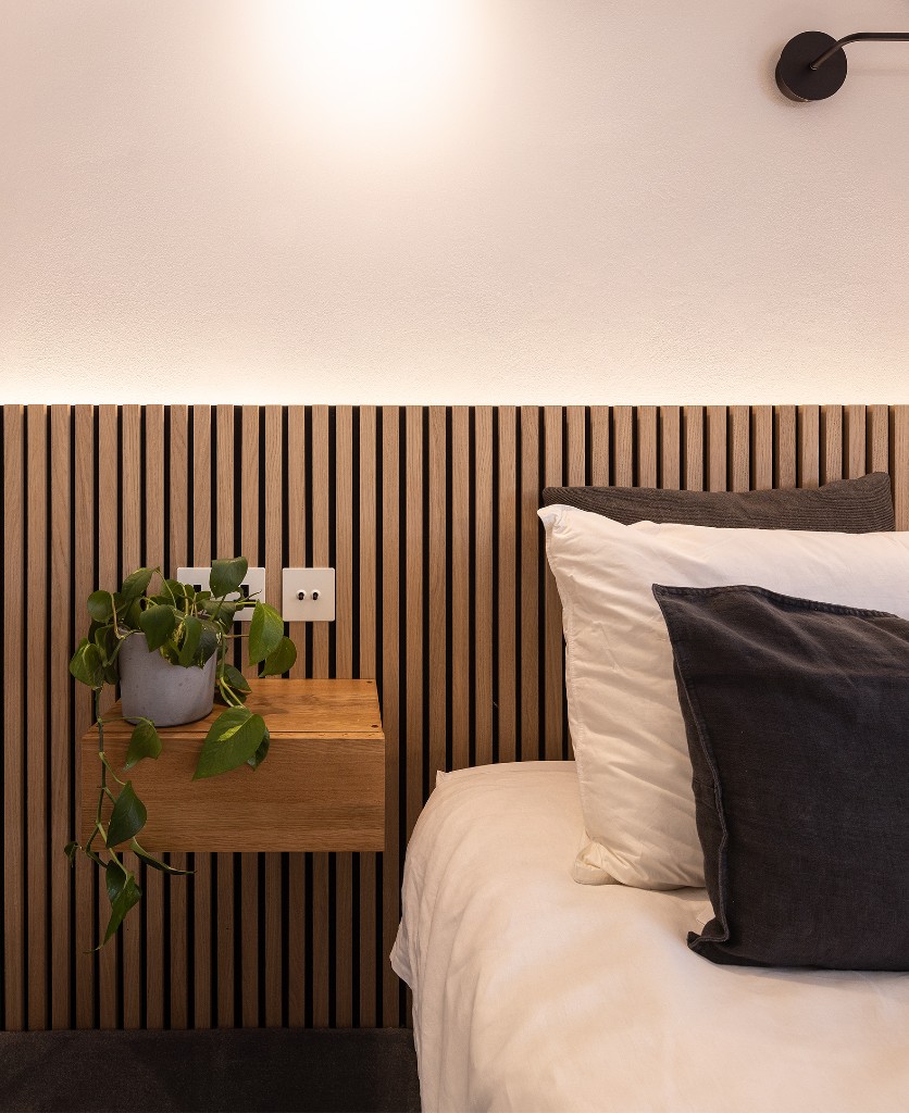 white and black double toggle switch installed on a wooden panelled wall beside a bed