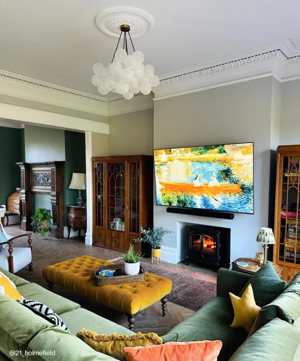 A large frosted bubble chandelier in the centre of a large living room with a green sofa and dark wood accents.