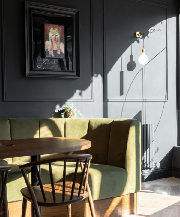 gold angler wall lamp instaled on a dark grey panelled wall in a kitchen diner