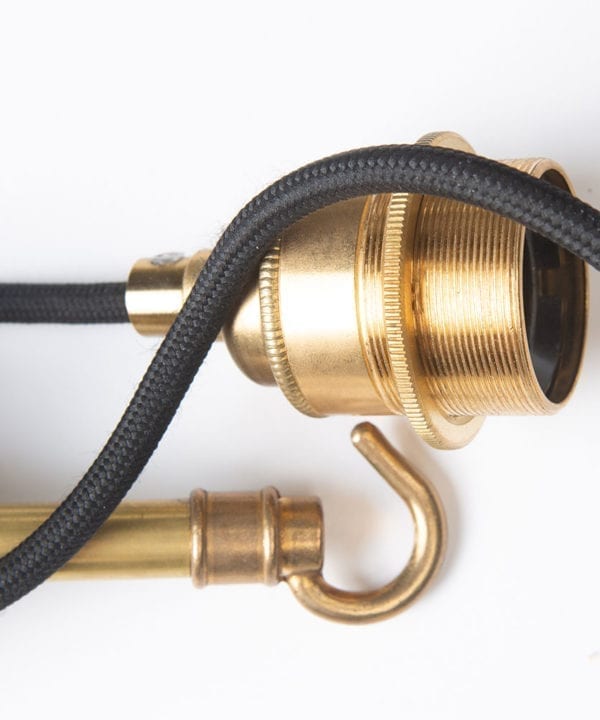 closeup of brass bulb holder, hook and black fabric cable against white background