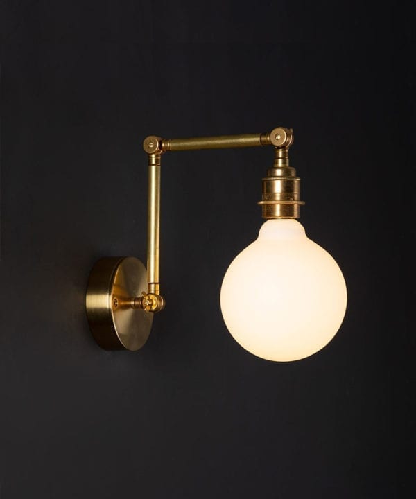 fender brass wall lights with lit opal bulb against black background