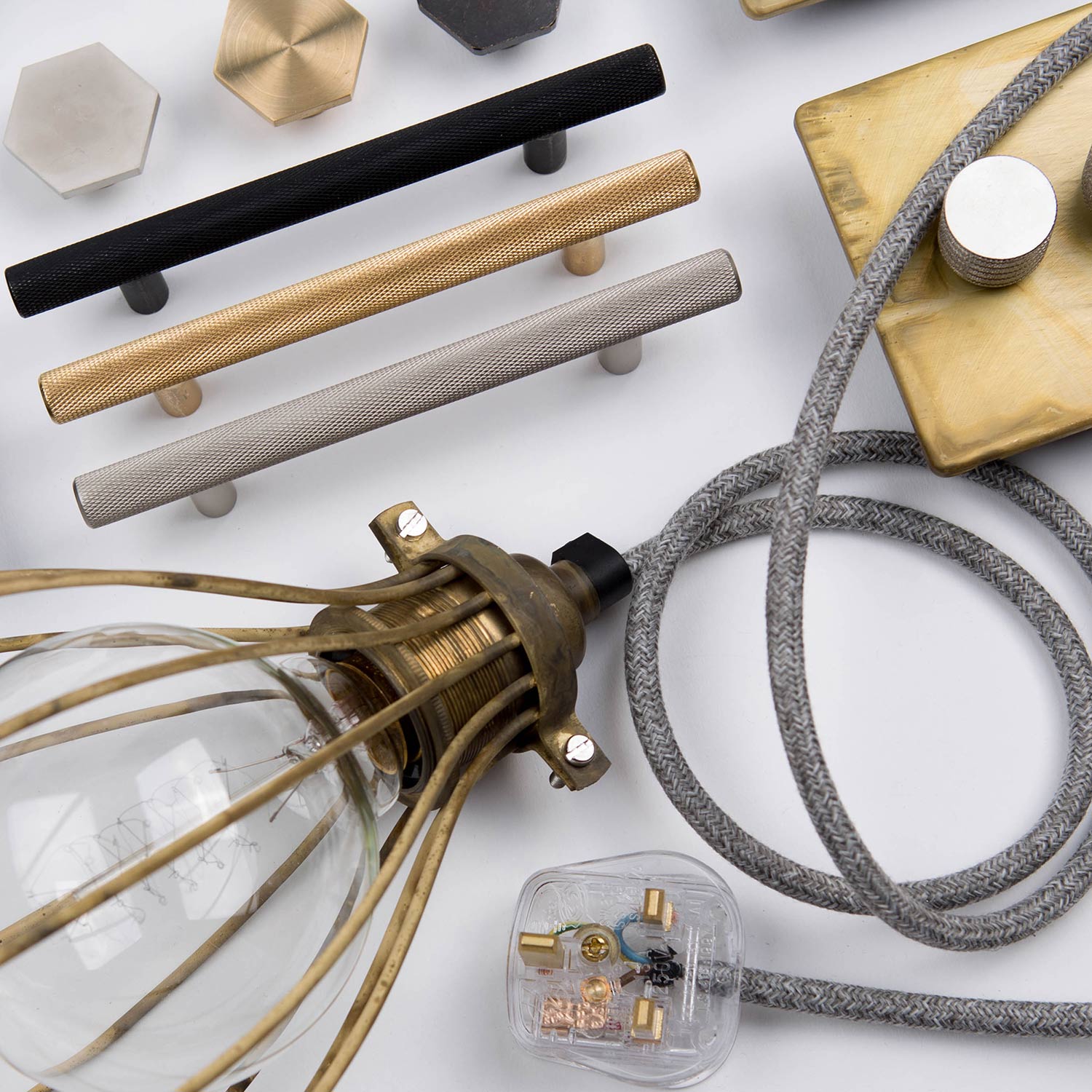 flatlay of skyscraper handles, smoked gold double dimmer, smoked gold balloon cage and bauhaus knobs against white background