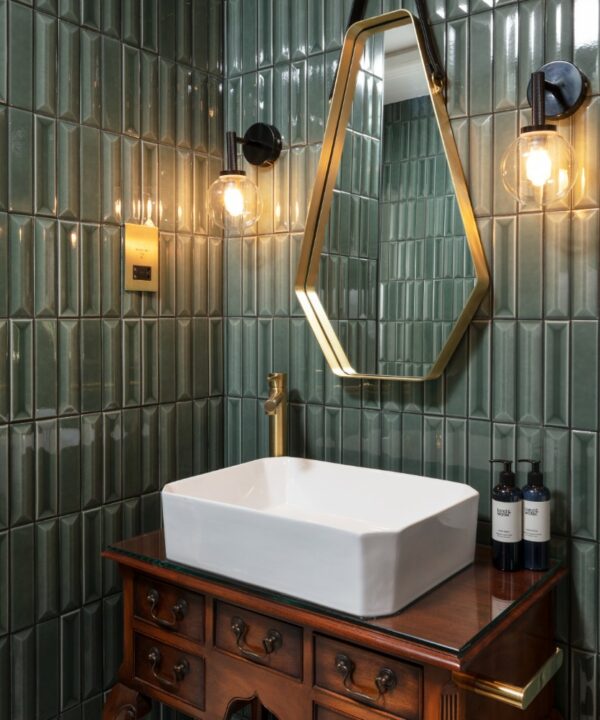 gold and black shaver socket in a green tiled bathroom