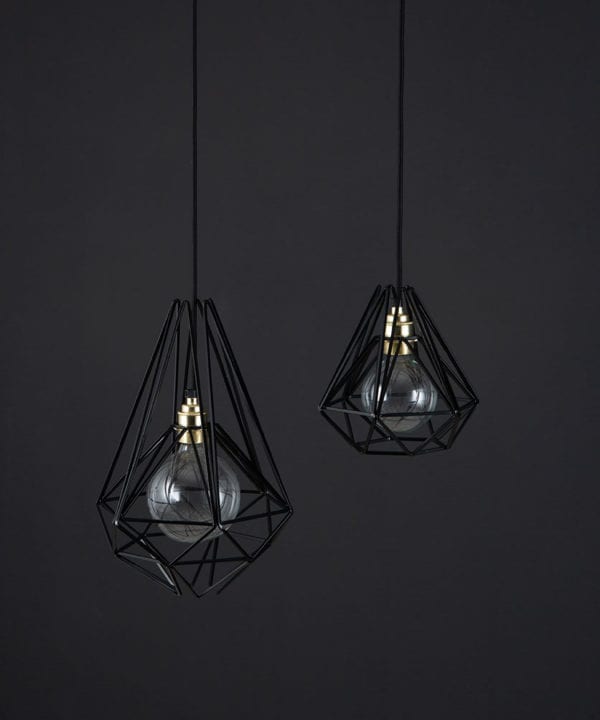 cage pendant light black two black metal diaamond shaped cage light shades with gold bulb holders suspended from black fabric cable against dark grey wall
