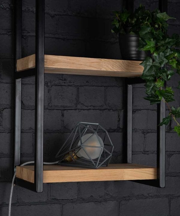 Grey cage shade table lamp on wooden shelf with frosted bulb switched off