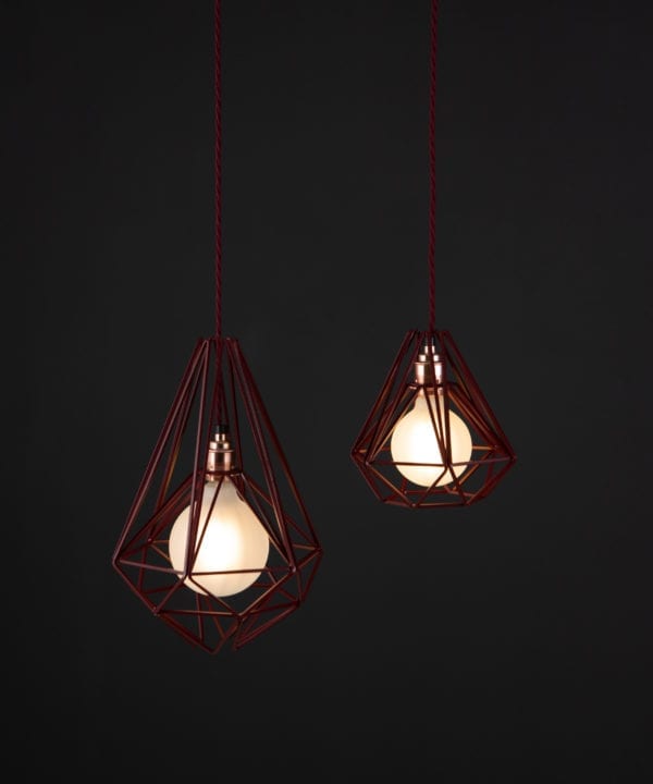 burgundy cage light with frosted bulbs suspended from burgundy twisted fabric cable against black background