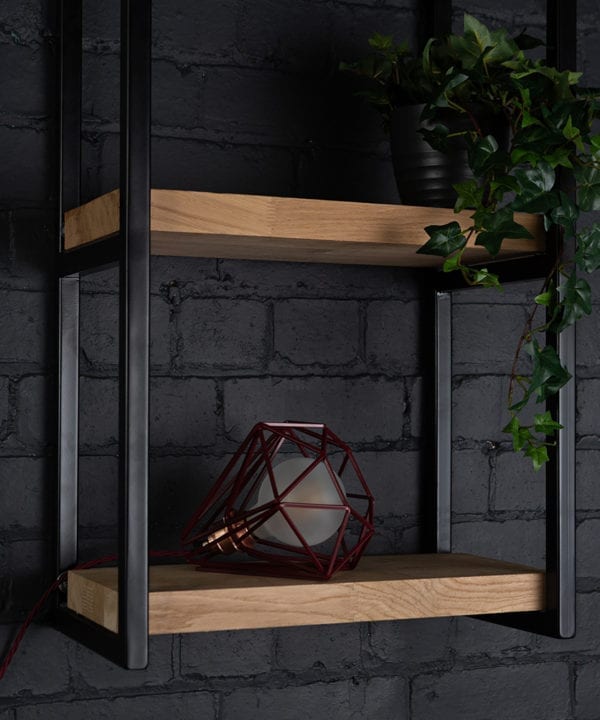 Burgundy cage shade table lamp on wooden shelf with frosted bulb switched off