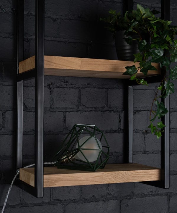 Green cage shade table lamp on wooden shelf with frosted bulb switched off