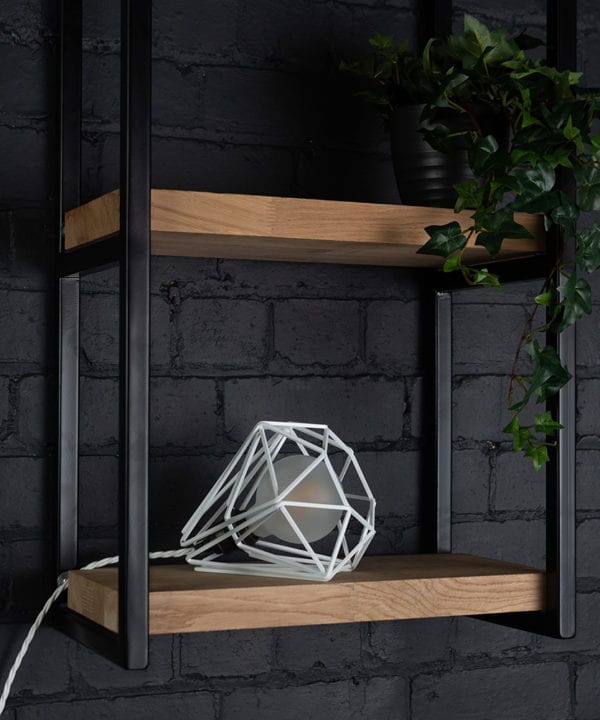 White cage shade table lamp on wooden shelf with frosted bulb switched off