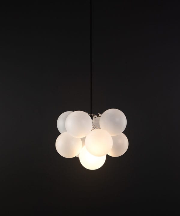 frosted glass bubble chandelier with 8 glass orbs and 1 silver bulb holder suspended from black cable against a black wall