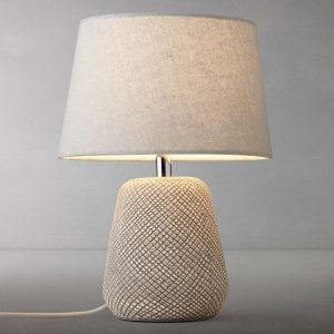 stone coloured table lamp with textured base against grey background