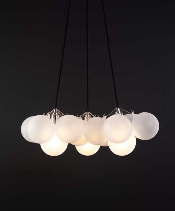 frosted bubble chandelier pendant light featuring 12 frosted baubles and silver bulb holders suspended from black fabric cable against a black wall