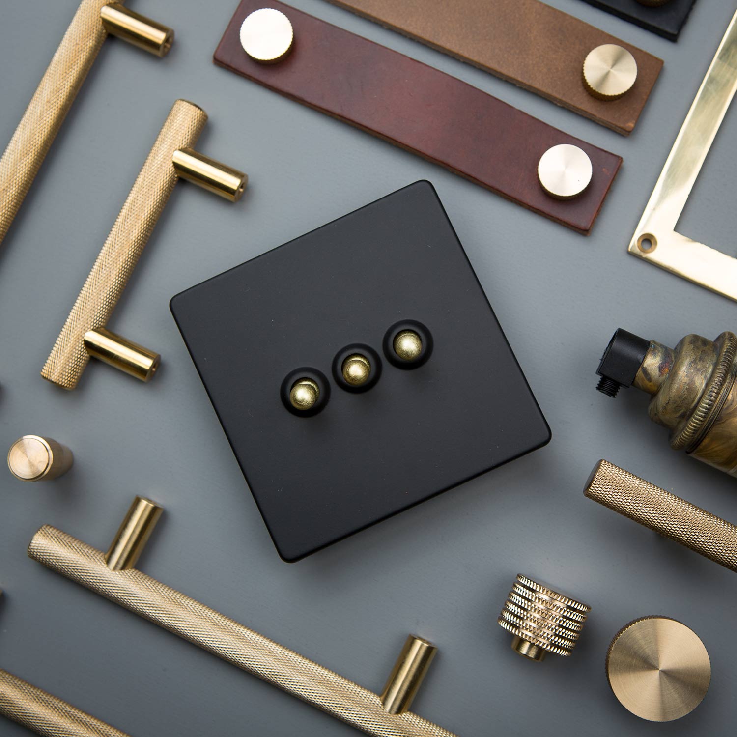 flat lay of gold and black triple dimmer, skyscraper handles, thor leather handles and various kitchen drawer handles