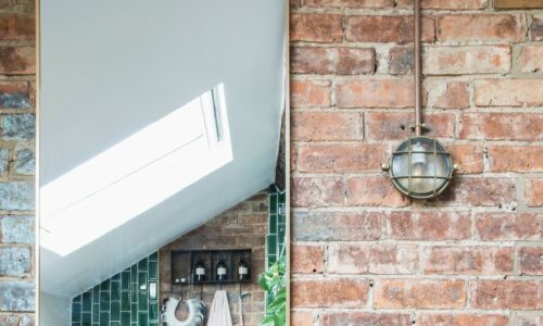 mark silver bulkhead light fitted on an exposed brick wall in a bathroom