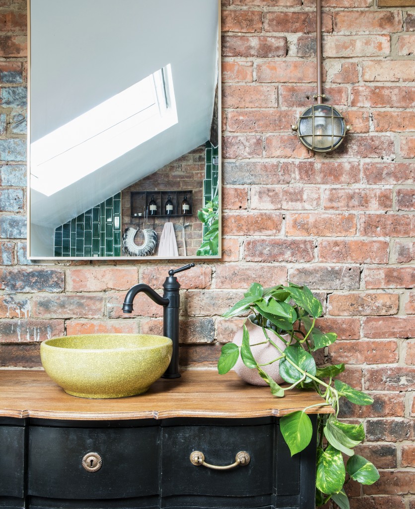 mark silver bulkhead light fitted on an exposed brick wall in a bathroom