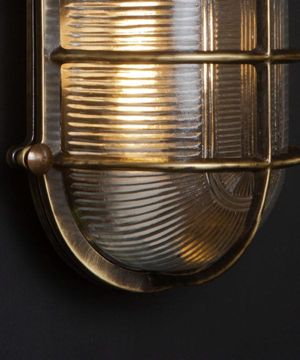 close up of aged brass lit big steve bulkhead on black wall