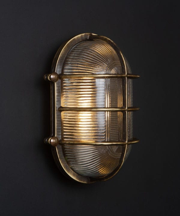 lit aged brass big steve bulkhead light on black wall