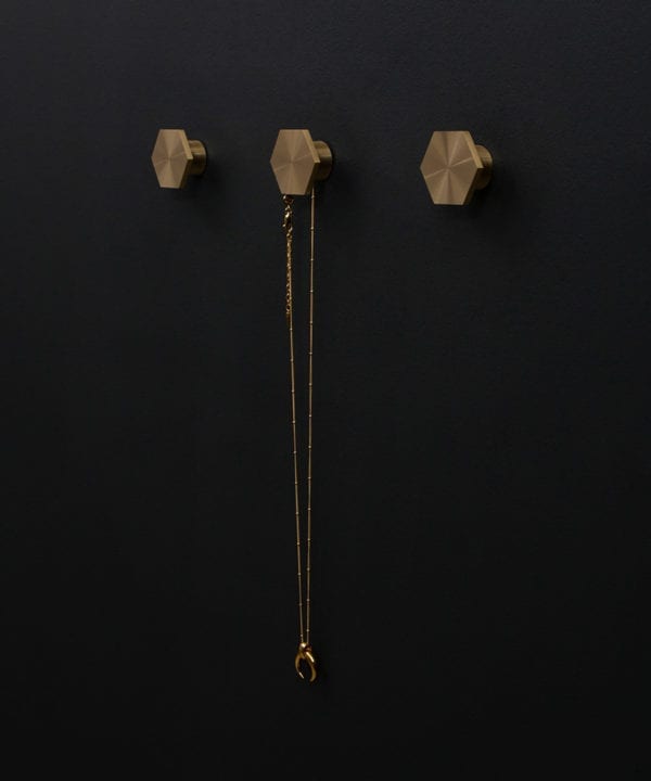 series of three bauhaus hexagonal modern coat hooks secured to a black wall