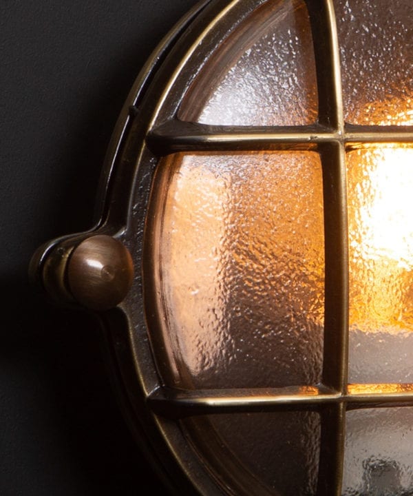 mark aged brass bulkhead light close up against black background