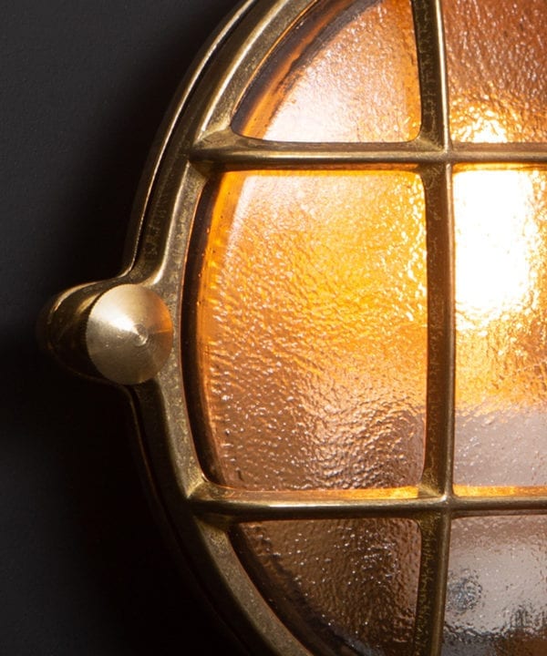 mark brass bulkhead light close up against black wall