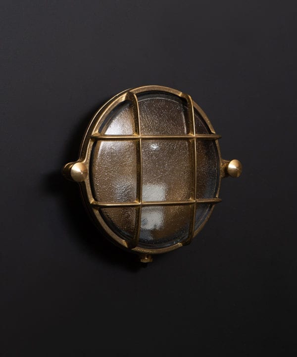 mark brass bulkhead light with unlit bulb against black wall