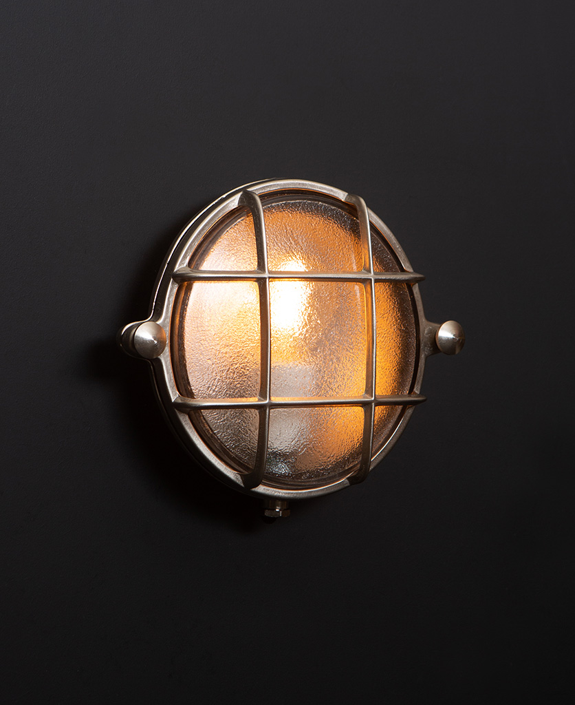 Mark silver bulkhead light with lit bulb on black wall