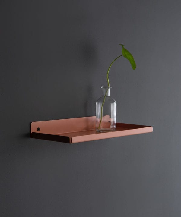 pink chai metal wall shelf with glass vase on a dark grey wall