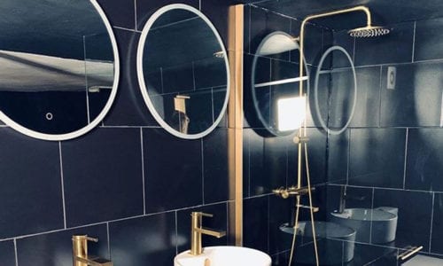 gold skyscraper handle with plate on black drawer in black, white and gold bathroom