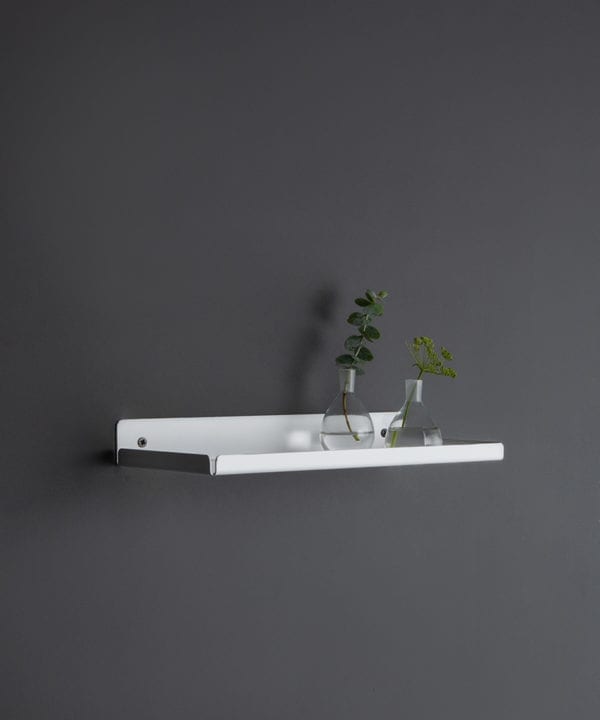 white wall shelf with glassware and vases on a dark grey wall