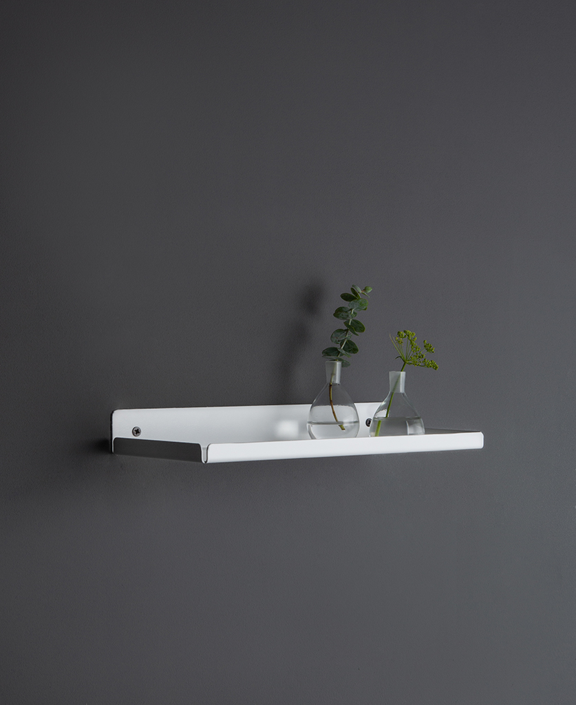 white wall shelf with glassware and vases on a dark grey wall