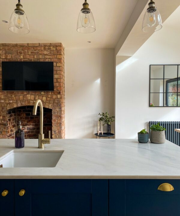 gold swan necked tap over a white sqaure basin on a navy and white marble kitchen island