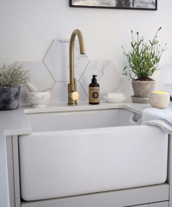 gold tinkisso tap installed above a white sink in a white and marble kitchen