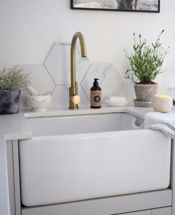 gold tinkisso tap installed above a white sink in a white and marble kitchen