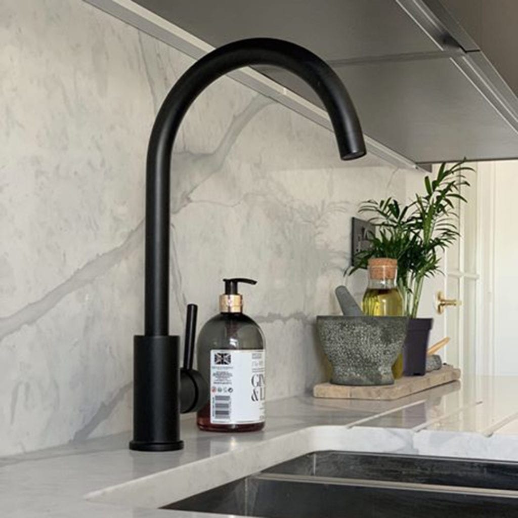 black tinkisso tap against white marble splashback in a kitchen