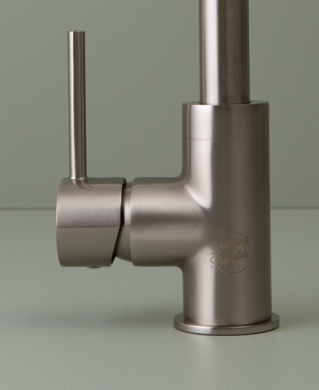 silver kintampo tap logo and handle close up on grey-green background