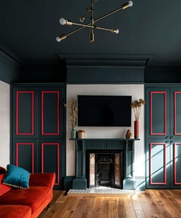 brass Tinkisso arm light in a dark blue room with red panelling and red sofa