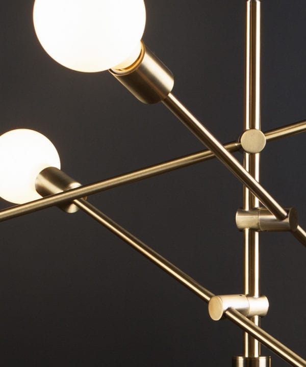 closeup of gold trikonsana pendant light with opal globe bulbs against black background