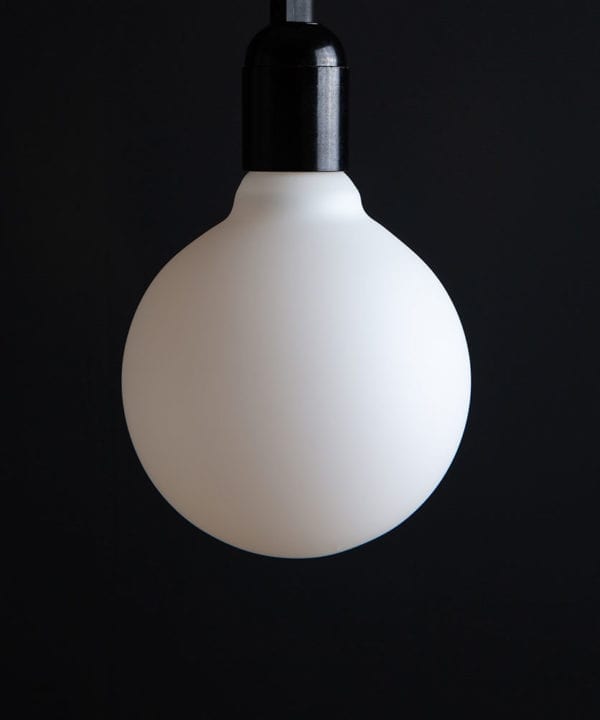 Unlit Aurora decorative light bulbs suspended from bakelite bulb holder against black wall