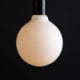 Lit Aurora decorative light bulbs suspended from bakelite bulb holder against black wall