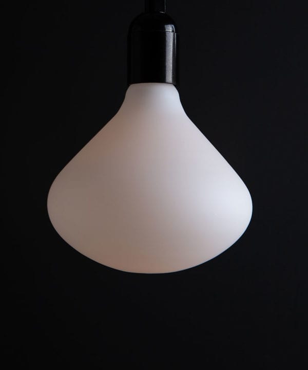 Unlit Nova decorative LED light bulb suspended from black bakelite bulb holder against black wall