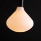 Lit Nova decorative LED light bulb suspended from black bakelite bulb holder against black wall