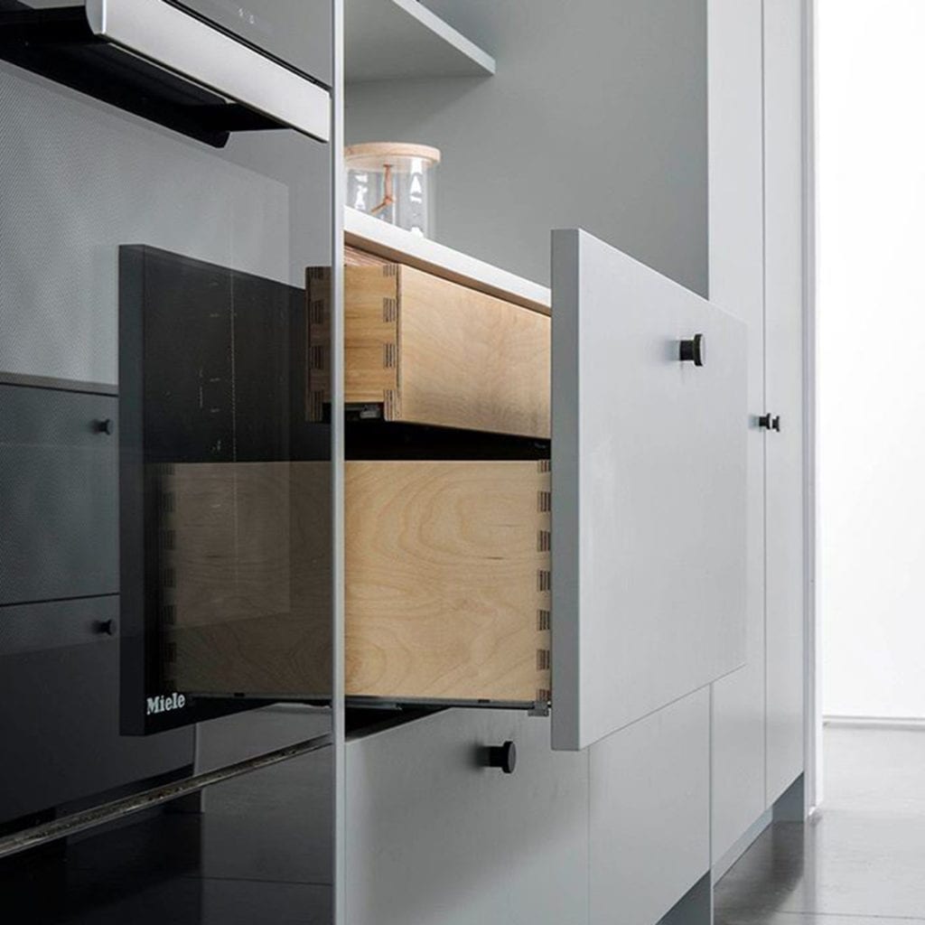 black modernist drawer knobs on white drawers and cupboards in a kitchen