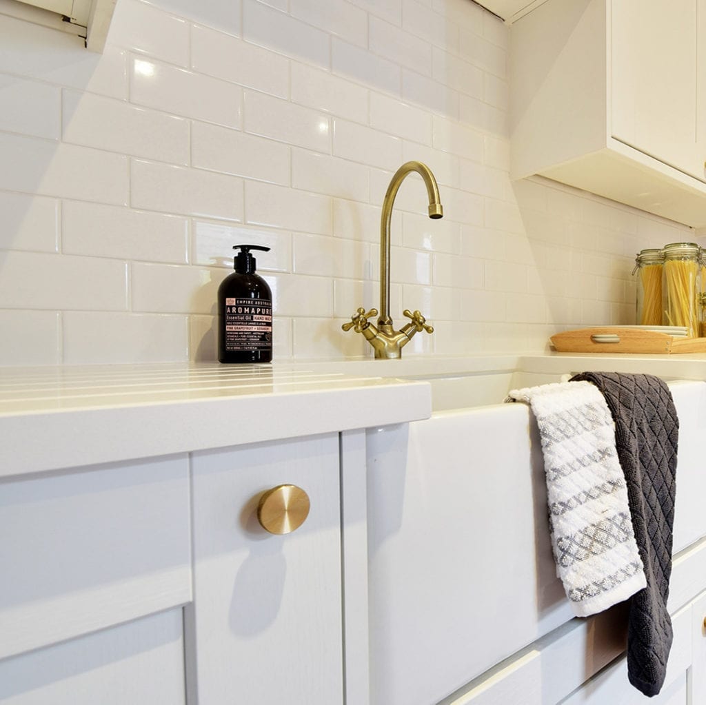 gold modernist drawer knob on a white kitchen cupboard