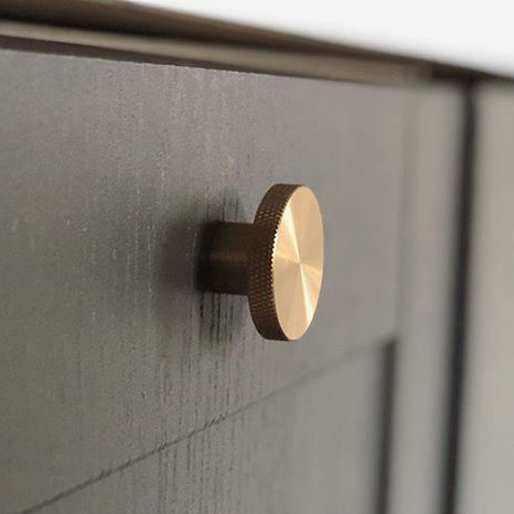 brass modernist large knob on a dark grey cupboard