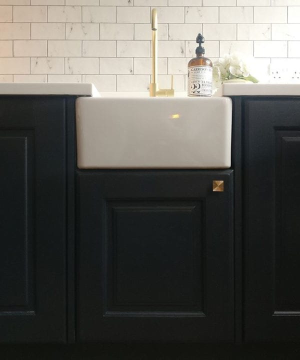 gold expressionist knob on a black under sink cupboard in a monochrome kitchen
