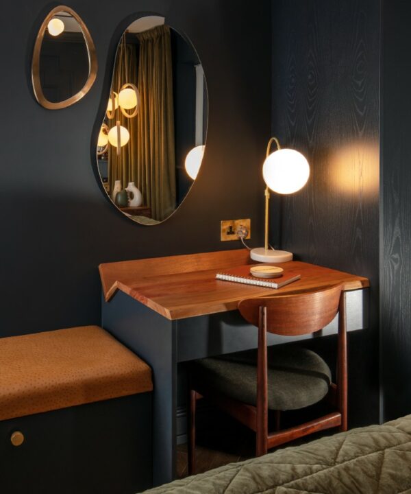 smoked gold double unswitched socket installed on a black wall above a wooden and black desk