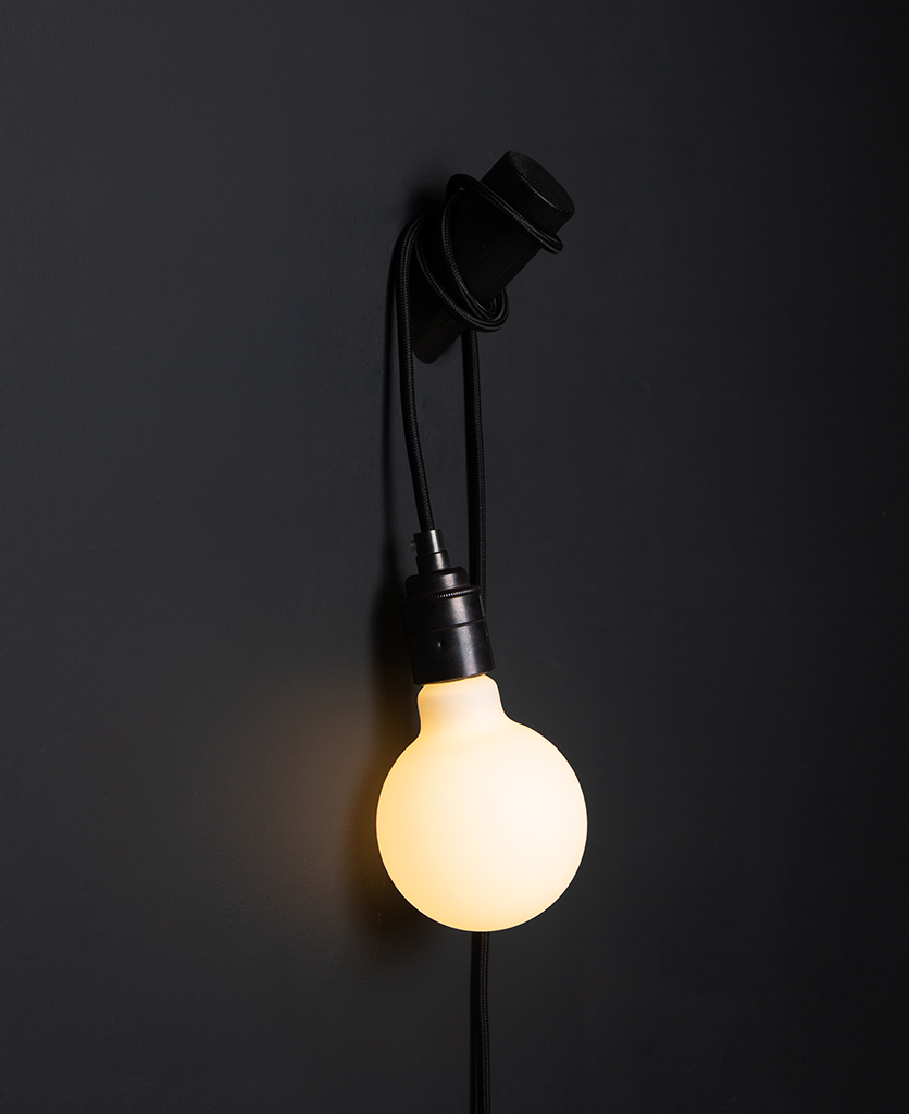 black peg lamp with black cable against black wall