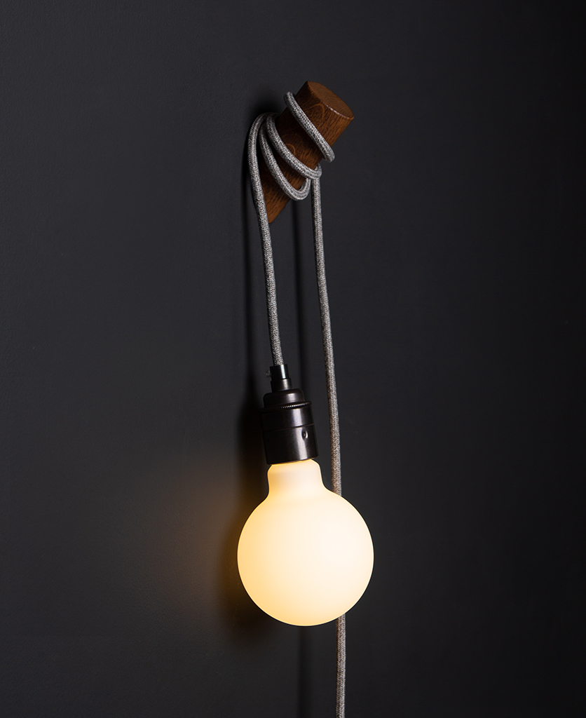 oak peg lamp with grey cable against black wall