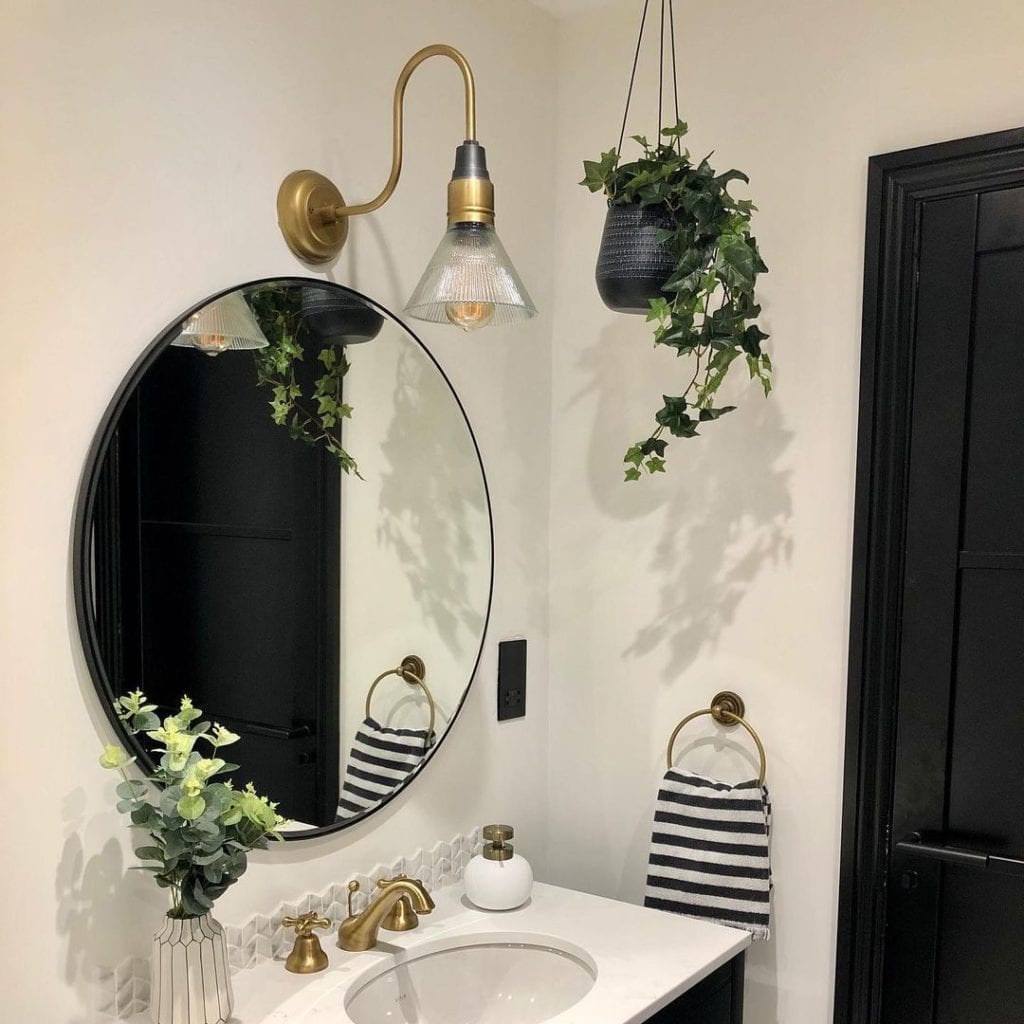 Ivy artificial trailing plant in black pot hanging from the ceiling in a black and white bathroom